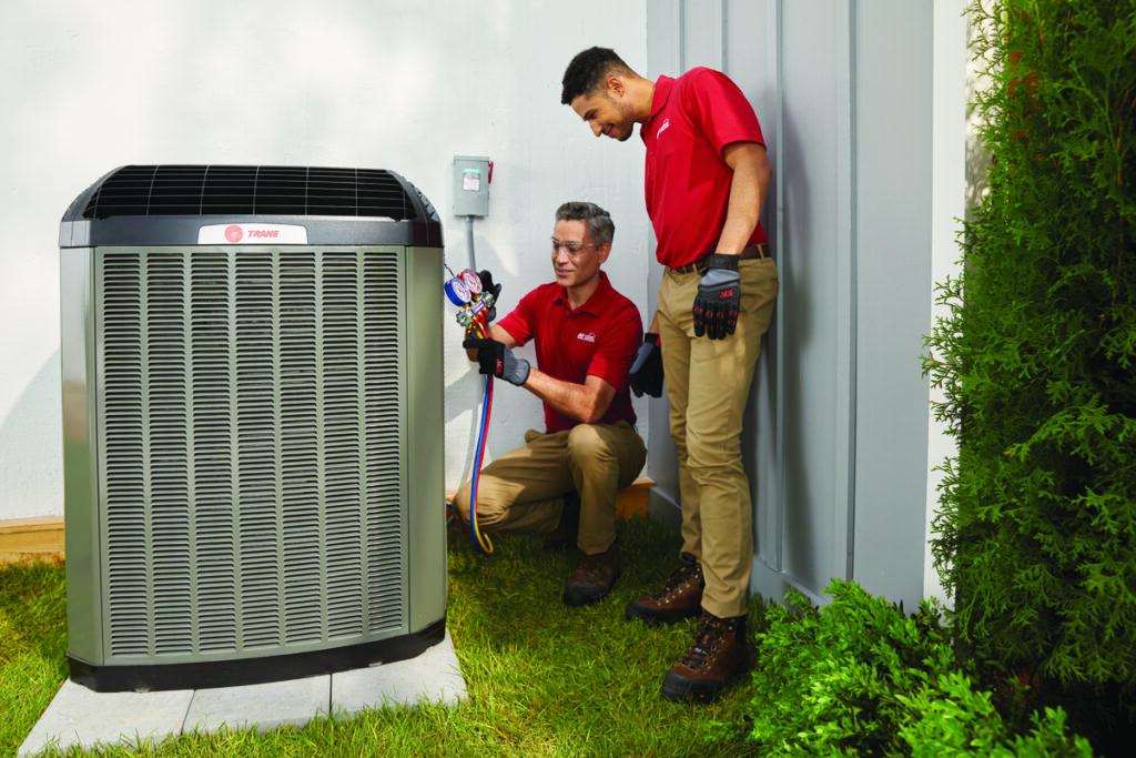 HVAC technicians working on an outdoor air conditioner unit