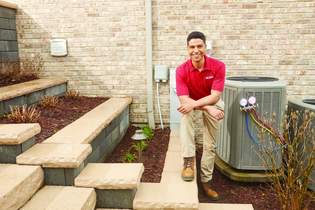 HVAC technician next to an outdoor air conditioning unit
