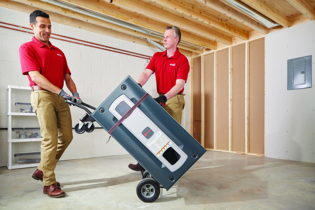 Two HVAC technicians delivering a furnace for installation
